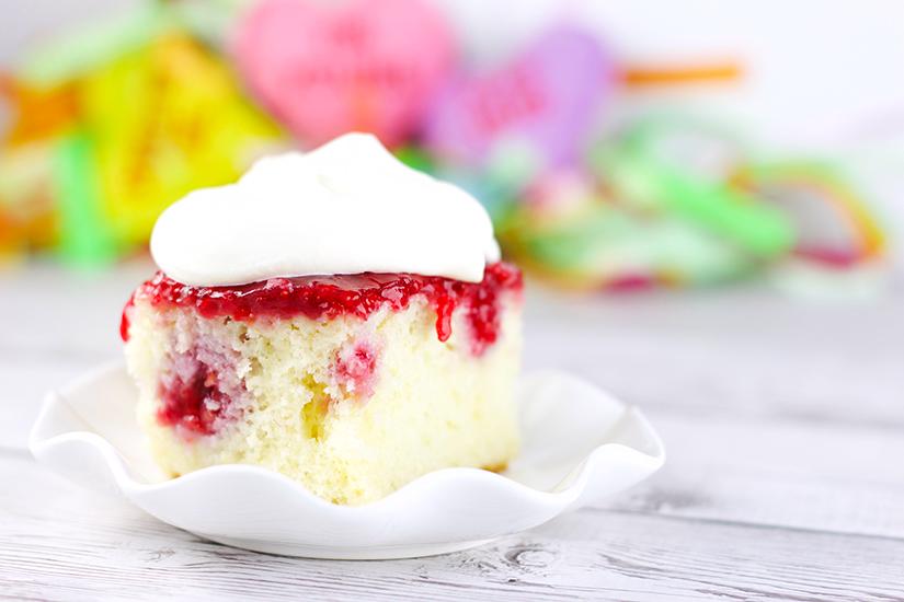 Fresh Raspberry Poke Cake Dessert Recipe! Perfect for holidays and birthdays with light frosting that won't weigh you down. Recipe on www.embellishmints.com