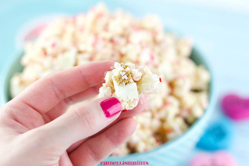 This White Chocolate Peanut Butter Popcorn is a perfect Valentine's Day treat! A blend of white chocolate, peanut butter, peanuts, and Reese's White Chocolate Peanut Butter Cups! Find the recipes on www.Embellishmints.com